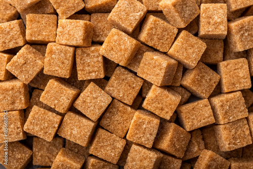 Pile of brown sugar cubes on white background.