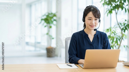 Japanese customer support woman with headset typing on laptop