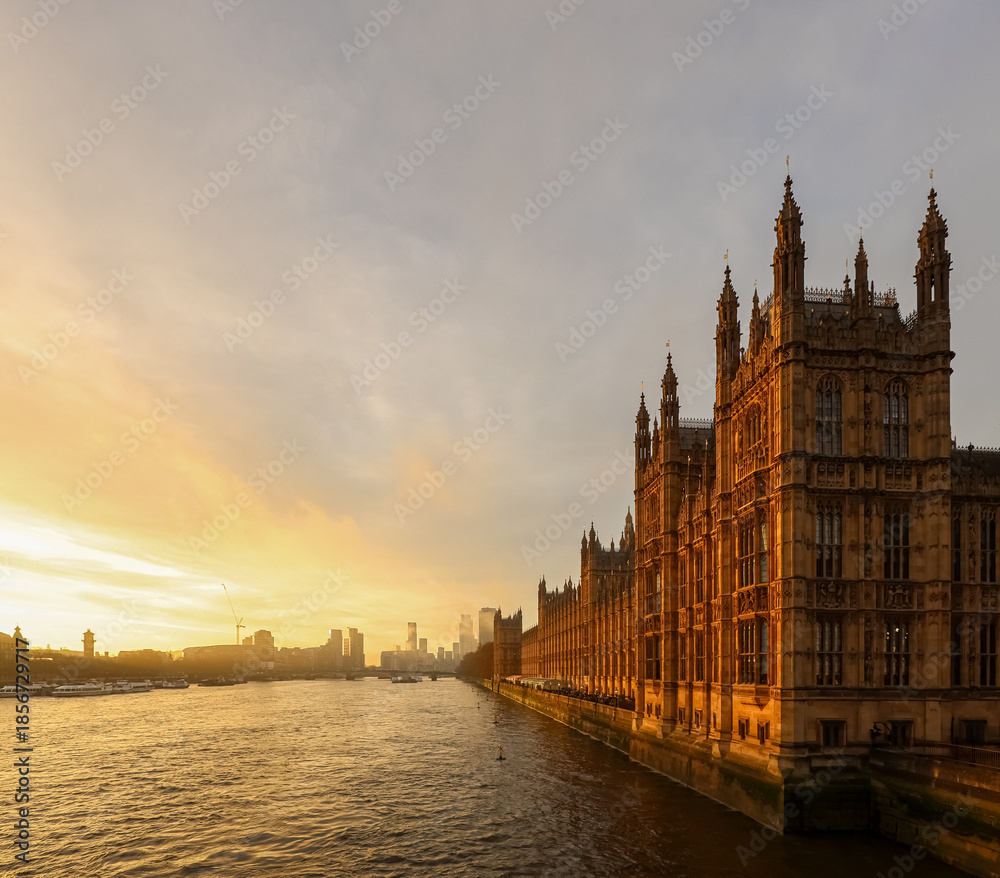 Fototapeta premium Palace of Westminster glowing with golden light, standing alongside the River Thames as the sun sets over the London skyline