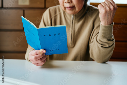 Tableau sur toile 年金手帳を見つめてガッツポーズするシニア女性