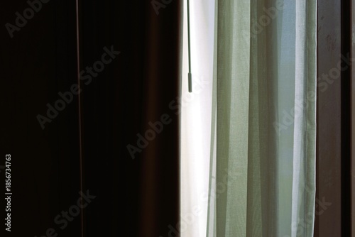 Photography a soft morning light filtering through semi-transparent green curtains in a dark