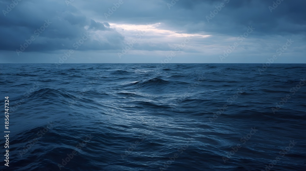 Fototapeta premium Turbulent deep blue ocean waves under a dramatic cloudy twilight sky conveying a powerful and atmospheric natural scene