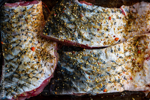 Marinated carp fish fillet with herbs and spices, closeup, top view
