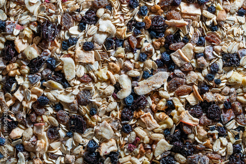 Whole grain oat muesli with dried fruits, nuts, raisins and berries, top view, closeup. Background of organic muesli for breakfast