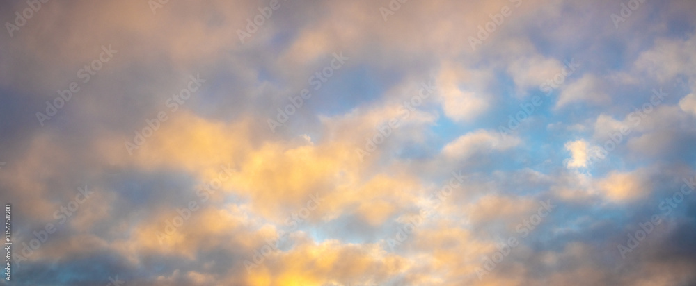 Fototapeta premium Gentle blue sky with soft yellow clouds at dawn, pastel atmospheric landscape with blurred cloud formations and calm mood