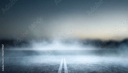 Dramatic long shot of an empty asphalt road disappearing into thick, swirling fog under a subdued sky, creating an atmospheric and mysterious scene of travel and unknown destiny