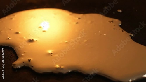 Swirl of Oil: a close-up image showing a golden-hued oil spill on a dark surface, creating a mesmerizing visual texture