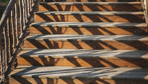 Close Up Of Sunlit Wooden Staircase With Shadows Of Leaves And Railing Leading Upward In Natural Outdoor Setting