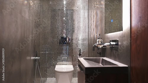 sleek, compact bathroom with a metallic mesh wall backdrop, modern sink, minimalist toilet, and dark wood vanity; clean lines and industrial aesthetic