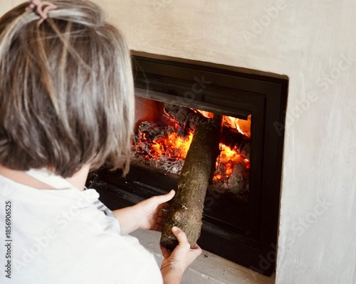 Close-up of a person starting a fire in a modern wood stove, domestic heating and comfort.