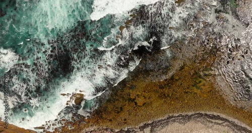 Aerial top down view of ocean waves in slow motion, in Cape of Good Hope in South Africa. Powerful turquoise surf over the rocky coastal shoreline. Ideal for cinematic travel and nature footage