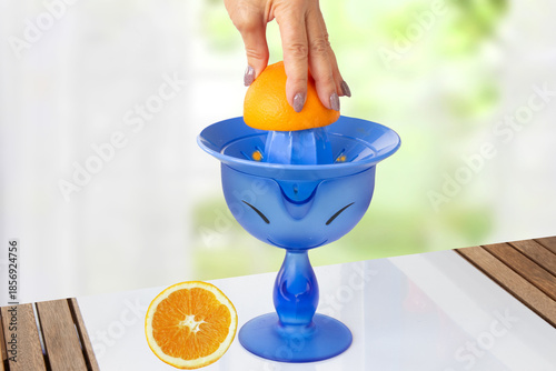 Fotografie Womens hand making fresh orange juice with lemon squeezer which stands on table