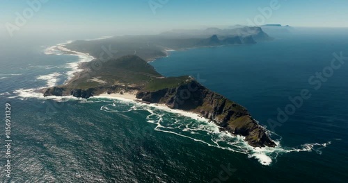 Establishing Aerial orbit shot of Cape of Good Hope in South Africa. Dramatic cliffs at coastline, turquoise waters, sandy beach, and green terrain on sunny day. Ideal for travel and documentary use