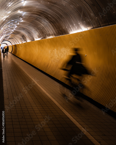 Photography Blurred cyclist in illuminated underground tunnel with leading lines
