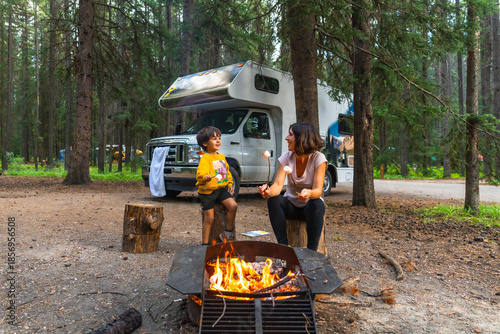Family roasting marshmallows at campfire near camper van in banff national park