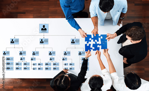 Fotografija Diverse team members gather around a table, engaging in a collaborative puzzle game that promotes strategic thinking and teamwork during a work meeting