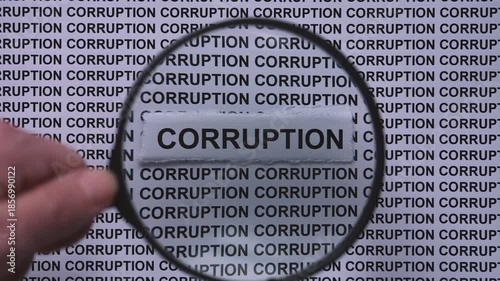 A person with a magnifying glass in his hand magnifying the words Corruption on a newspaper print background. Close up.
