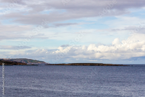 Calm Seascape With Rocky Island and Wide Horizon Under Soft Cloudy Sky