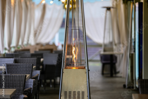 Outdoor Gas Patio Heater with Open Flame on Restaurant Terrace, Modern Cafe Interior with Warm Lighting and Cozy Atmosphere