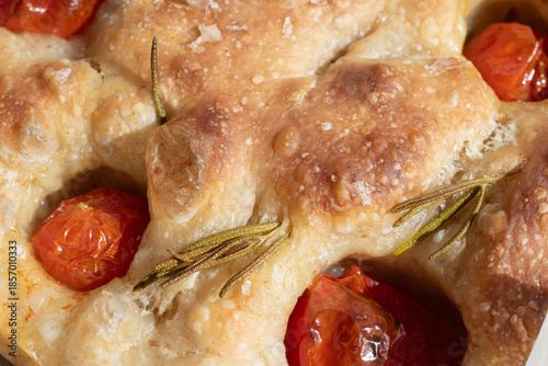 close up of a focaccia with tomatoes, rosemary and sea salt flakes