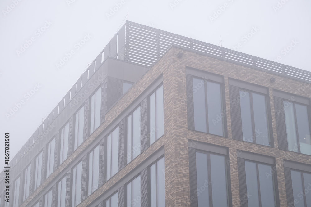 Fototapeta premium Modern apartment building facade in foggy urban environment