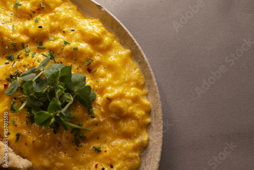 Photos Creamy scrambled eggs on naan, garnished with fresh chives and microgreens, buttersoft texture and golden hues, warm cafe lighting, chef preparation vibe, rustic plating for comforting brunch