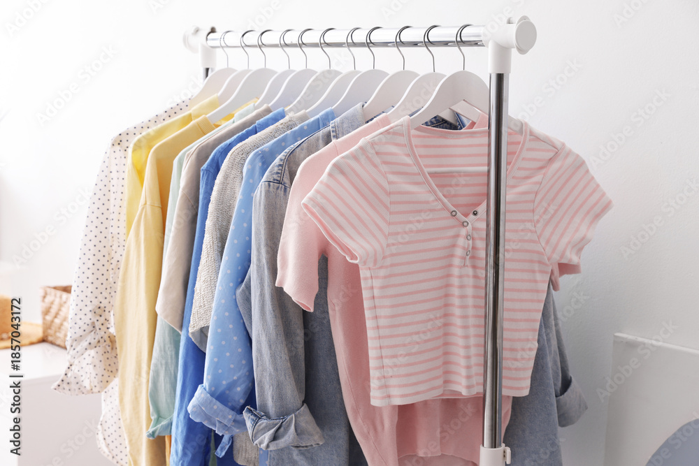 Obraz premium Different stylish clothes hanging on rack near white wall indoors, closeup