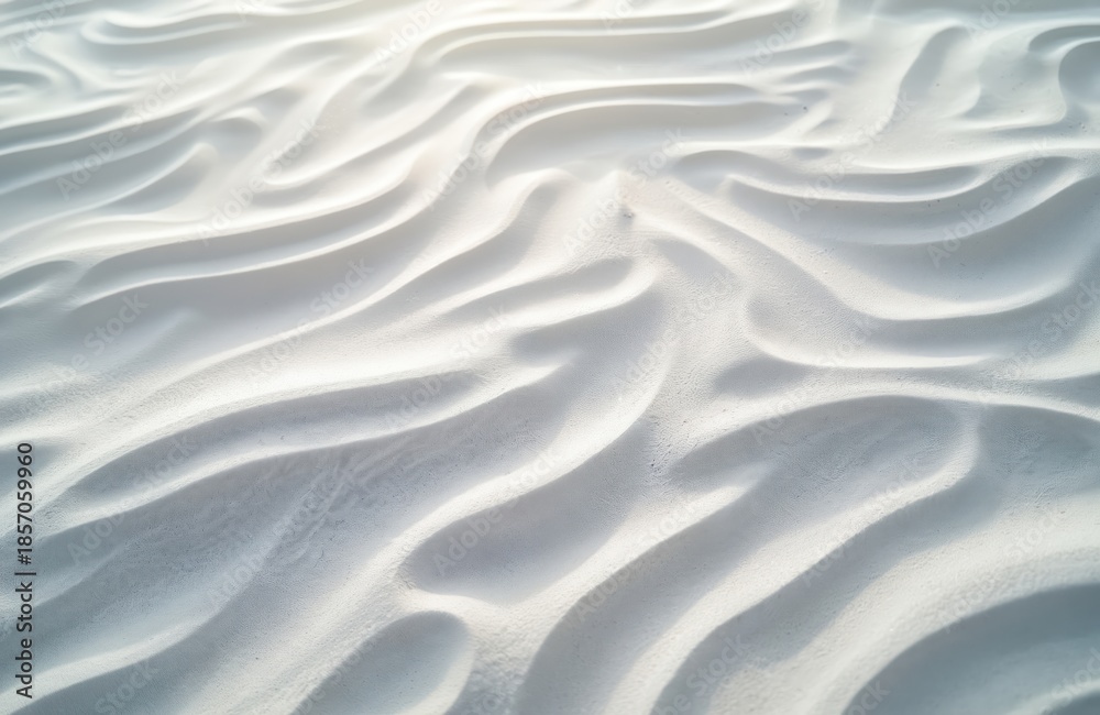 Obraz premium Close up abstract view of fine white sand dunes with flowing wave patterns. Soft light creates gentle shadows accentuating natural organic shapes, ideal for calm backgrounds.