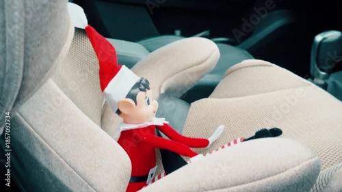 Close up of a festive Christmas elf doll placed on a modern car seat inside vehicle interior. Seasonal decoration concept combining holiday tradition family travel and everyday transportation