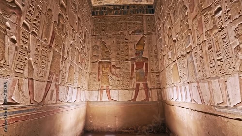 Interior view of ancient stone chamber with hieroglyphs, reliefs, and figures, with faded paint