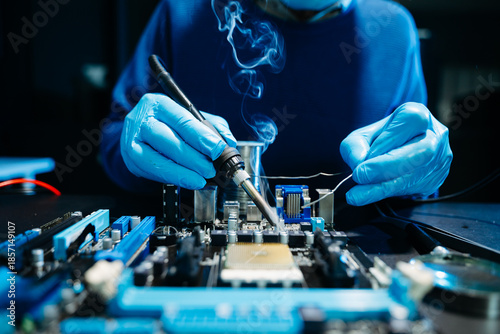 Fotografija Closeup of expert soldering a green PCB board using precision tools