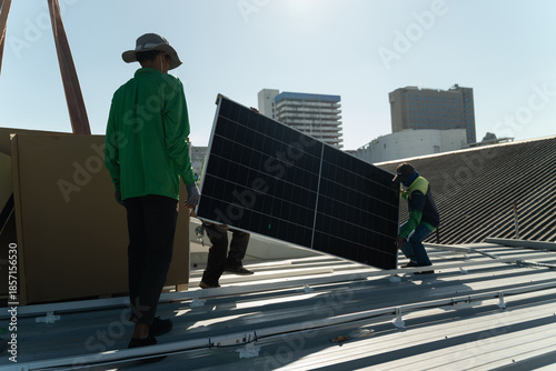 фотографія Workers install solar panels on a rooftop at a construction site in a city on a