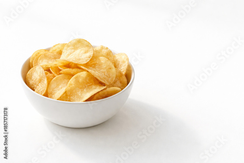 Foto A white bowl filled with crispy golden potato chips on a clean white background with a subtle shadow