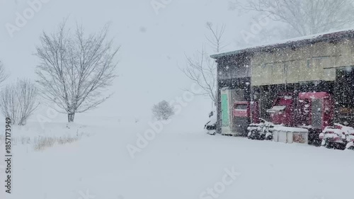 雪が降る田舎の風景　まき　冬　建物　小屋　農機具