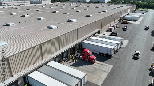 Large industrial building logistics center with trucks at loading docks aerial view