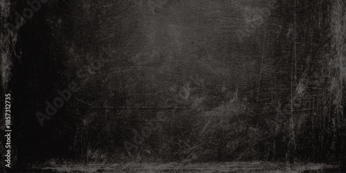 A dark textured background resembling a weathered chalkboard or black wall with subtle light variations
