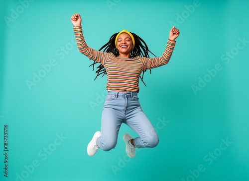 A joyful young woman jumping joyfully with her arms raised in celebration