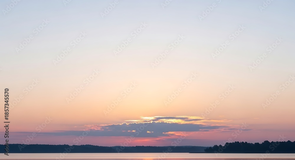 Fototapeta premium Serene Sunset Over Calm Water with Distant Tree Line.