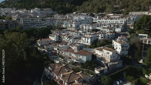 Drone tracking back to reveal dense area of luxury hillside residential buildings in Mijas Pueblo, Spain, charming Mediterranean town, famous for their traditional white washed architecture.