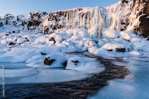 Foto Winter outdoor scene showing a snow-covered river near the partially frozen Oxararfoss Waterfall in Thingvellir national park in the Golden circle in Iceland