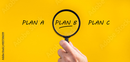 Fotografija Hand holding magnifying glass focusing on plan b