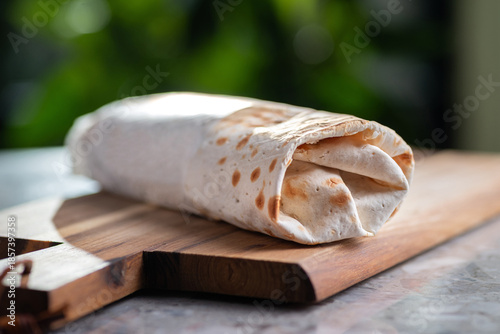 Shawarma, sandwich, gyro, fresh roll of lavash, doner kebab. Whole, not cut. Served on wooden plate. Traditional Eastern oriental snack, street food menu