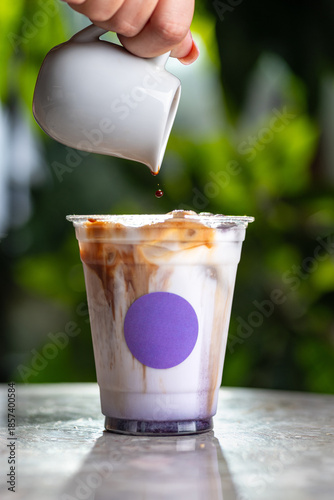Iced latte in a tall glass, hand-poured, against a green background with a shadow.