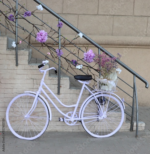 White bicycle near stone wall and staircase decorated with flowers.