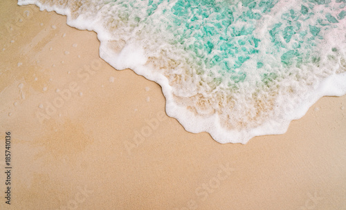 Bild auf Leinwand A close-up, high-angle of a gentle white-foamed ocean wave washing onto a smooth