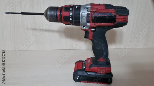 Static studio shot of a red and black cordless power drill standing upright on a workbench shown from left side profile highlighting robust design