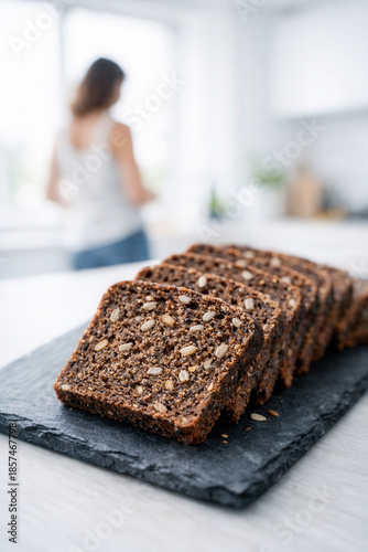Slices Of Dark Rye Bread With Seeds On Black Slate Board In A Bright Modern Kitchen