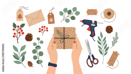 Overhead view of hands holding a brown paper gift box surrounded by crafting supplies like pinecones, berries, twine, and a glue gun.