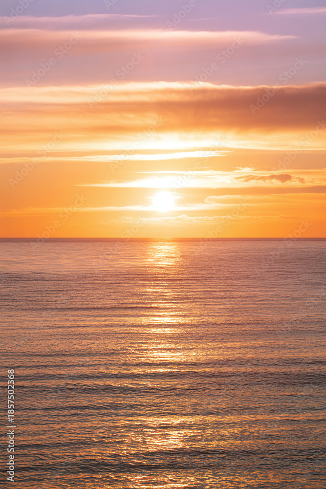 Fototapeta premium Sunset over Calm Ocean Water with Vibrant Orange Sky