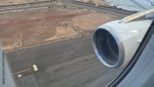 Plane landing filmed from inside the cabin through window, showing jet turbine, ocean coastline and final approach onto Lanzarote runway, smooth arrival at island airport with travel perspective.